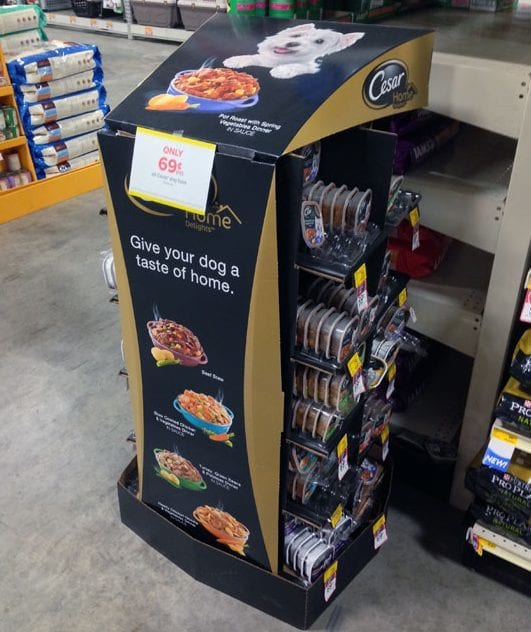 A Cesar dog-food floor display with product trays and a header card, in a store aisle
