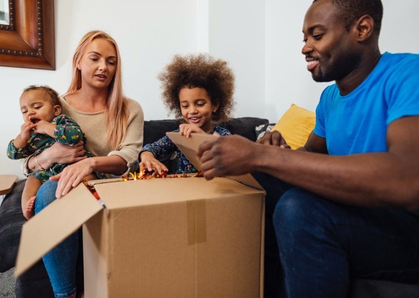 A family on a sofa opening a delivered cardboard box together