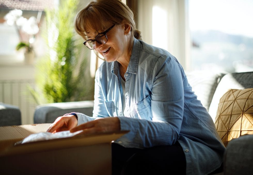 A woman smiling as she opens a delivered package